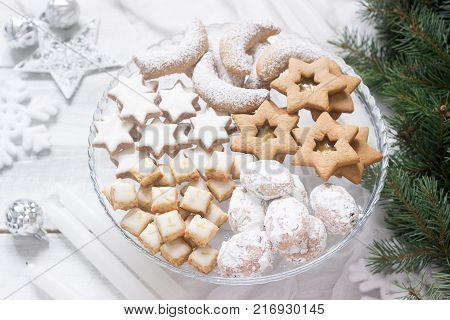 Festive cookies assorted vanilla crescents, cinnamon stars, gingerbreads and cubes and stollen on a festive background. Selective focus.