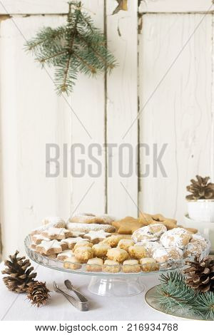 Festive cookies assorted vanilla crescents, cinnamon stars, gingerbreads and cubes and stollen on a festive background. Selective focus.