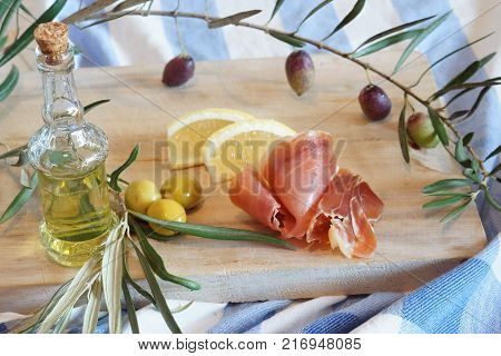 Breakfast in the kitchen with a jamon and stuffed olives, a bottle of olive oil and a twig with olives.