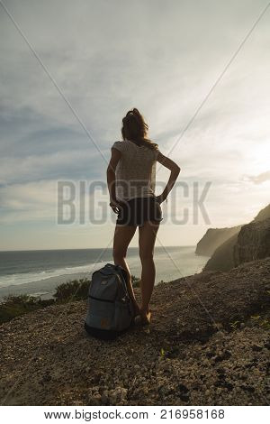 Tourist girl with backpack standing on the clidd and enjoying the view.