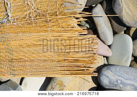 tattered Mat washed up by the sea on a pebble beach