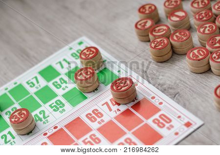 Developing bingo table game old lotto game with wooden elements and cards bingo on a wooden background.