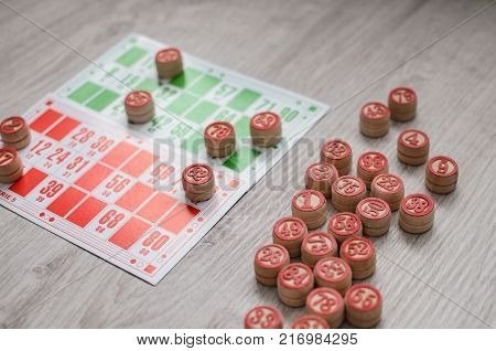 Developing bingo table game old lotto game with wooden elements and cards bingo on a wooden background.