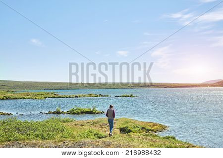 back view of woman on the shore of tne Thingvallavatn lake in Thingvellir National Park, largest natural lake in Iceland. Travel to Iceland.