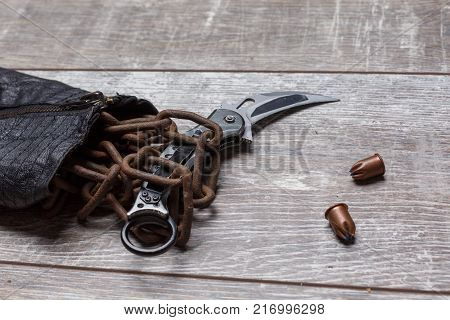 The knife is wrapped in a chain from a jacket next to bullets on a wooden background