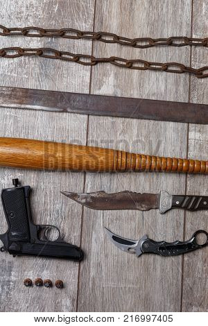 Weapons of chain bandits, machetes, bits, knives and a bullet with bullets lie horizontally on the wooden floor