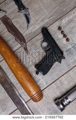 Weapons of bandits pistol with bullets, bat, knives, machetes and neatly laid out on a wooden background...