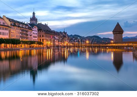 Town Hall, Water Tower, Wasserturm, And Traditional Frescoed Building Along The River Reuss At Sunri