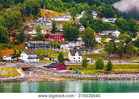 Norwegian Fjord Village Landscape With Low Fog Clouds, Mountains And Colorful Houses In Loen, Norway
