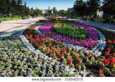 Russia, Irkutsk - July 7, 2019: Flower Bed, Fountain And Historical Building In Tikhvinsky Or Kirov 