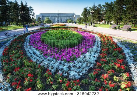 Russia, Irkutsk - July 7, 2019: House Of Soviets, Government Of The Irkutsk Region, Flower Bed And C