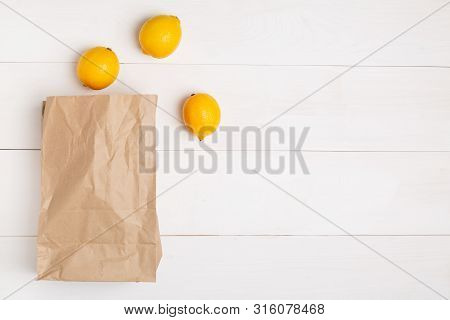 Paper Bag On Wooden White Background With Empty Space For Text. Flat Lay, Top View.