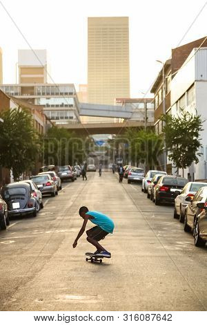 Johannesburg, South Africa - January 29 2012: Young Kid Skateboarding In The Empty Streets Of Mabone