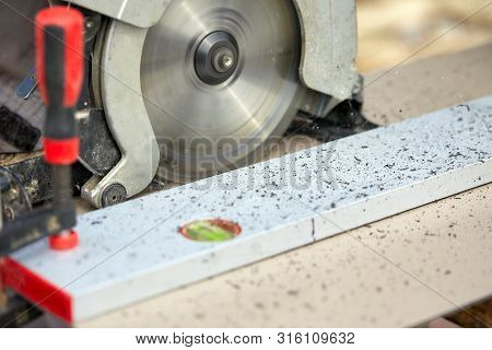 A Construction Contractor Worker Using A Worm-driven Hand-held Circular Saw To Cut Boards And Plasti