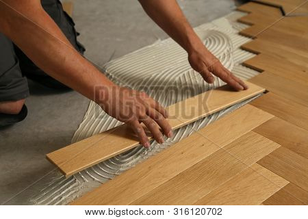 Worker Laying Parquet Flooring. Worker Installing Wooden Laminate Flooring
