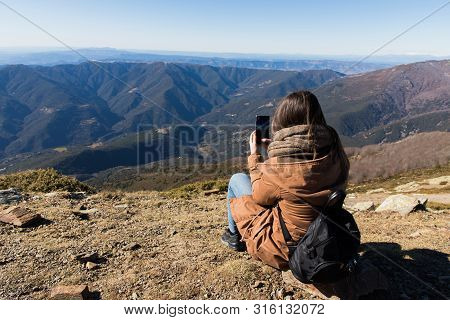 Beautiful Woman Sitting After Hiking And Taking Photo With Phone During Winter Or Autumn In Cataloni