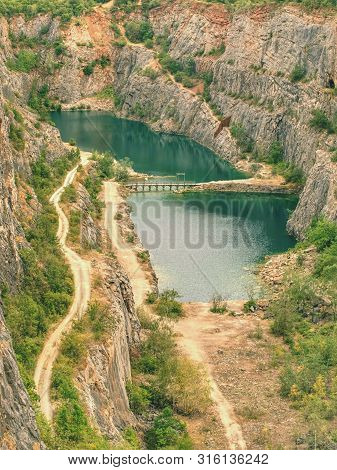 Deep Grand Canyon With Blue Lake At Bottom.  Many Roads Ands At Small Bridge In Middle