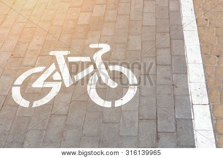 Bicycle Slab Paved Lane At Pedestrian Walking Area. Bike Symbol Painted With White Paint On Grey Pav