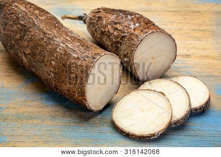 yuca cassava root with slices on wooden background