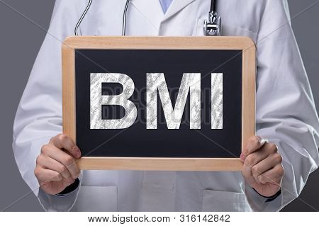 Mid-section Of Male Doctor Showing Wooden Slate With Bmi Text Against Grey Background