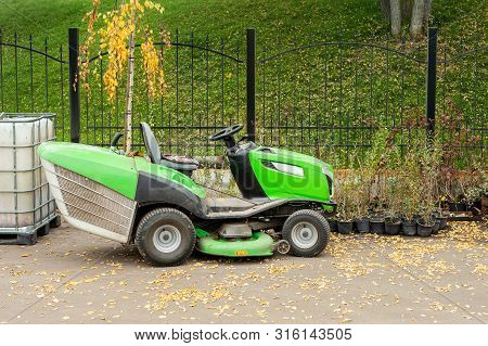 Big Industrial Lawnmower Machine Standing At Parking In City Park. Green Lawn Grass Mower Tractor At