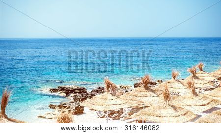 Rocky Beach And Crystal Turquoise Water Of Ionian Sea In Albania. Calm And Relaxing View With Umbrel