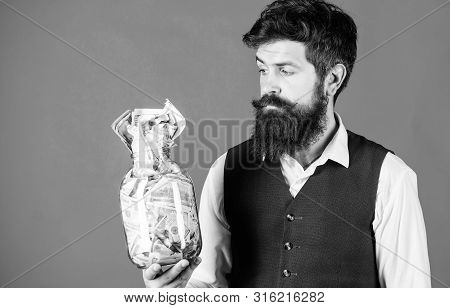 He Respects Money. Bearded Man Keeping Money In Glass Jar. Hipster Holding Jar With American Money. 