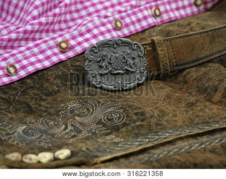 Close Up Bavarian Lether Belt With Coat Of Arms On Lederhose And Pink Check Shirt, Traditional Cloth