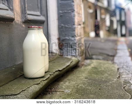 Fresh milk delivered by a milkman on a door step in glass bottles