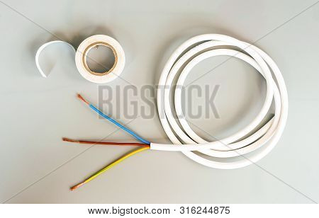 White Insulating Tape And Three-core Cable On A Gray Background