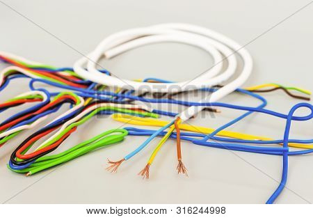 The Wires Of Several Types In Colored Insulation Are Curved In Different Shapes On A Gray Background
