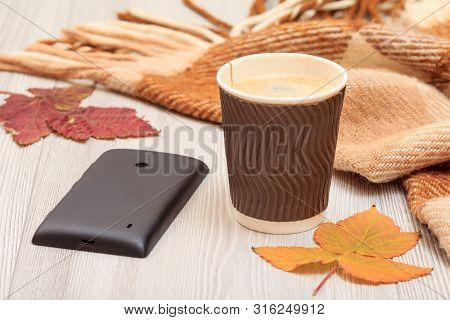Cup Of Coffee, Mobile Phone And Dry Leaves In An Autumn Still Llife.