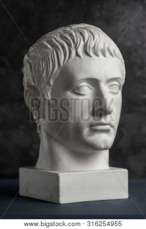 Gypsum Copy Of Ancient Statue Germanicus Head On Dark Textured Background. Plaster Sculpture Man Fac