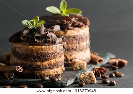Dark Chocolate Cakes On Black Slattern Board With Mint, Cinnamon, Coffee Beans On A Wooden  Backgrou