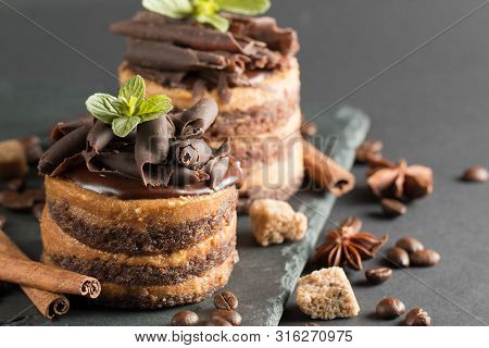 Dark Chocolate Cakes On Black Slattern Board With Mint, Cinnamon, Coffee Beans On A Wooden  Backgrou