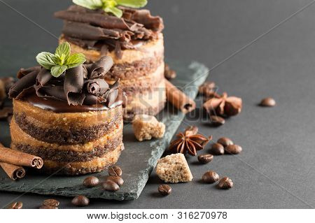 Dark Chocolate Cakes On Black Slattern Board With Mint, Cinnamon, Coffee Beans On A Wooden  Backgrou