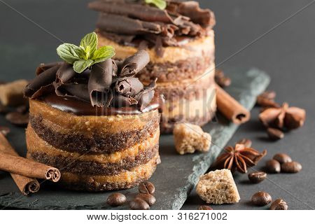 Dark Chocolate Cakes On Black Slattern Board With Mint, Cinnamon, Coffee Beans On A Wooden  Backgrou