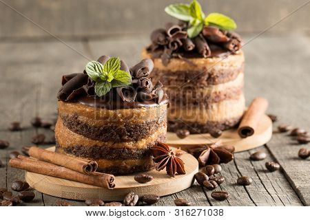 Dark Chocolate Cakes On Black Slattern Board With Mint, Cinnamon, Coffee Beans On A Wooden  Backgrou