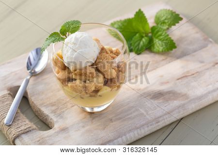 Apple Crumble Topping Vanilla Ice Cream Served With Melisa In Glass And Wooden Tray On Table.