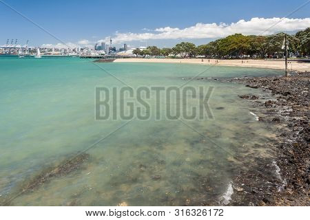 Auckland, New Zealand - December 9, 2012: Sandy Beach In Devonport With Auckland Skyline In Backgrou