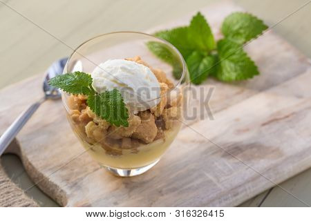 Apple Crumble Topping Vanilla Ice Cream Served With Melisa In Glass And Wooden Tray On Table.