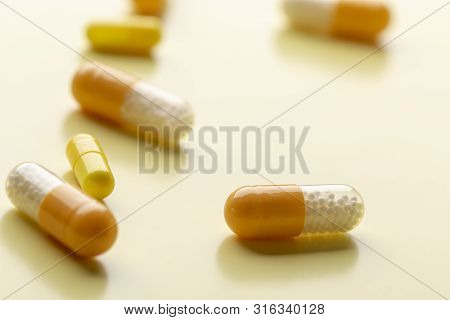 A Few White-yellow Drug Capsules On The Yellow Background