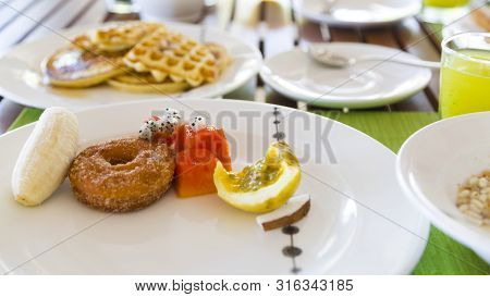Delicious Healthy Breaklfast Outdoors In A Wooden Table. The Breakfast Consists Of Fresh Fruit And W
