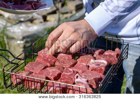 Summer Picinic. Raw Fresh Beef Meat Slices On A Grill With Onion Are Redy To Prepare.