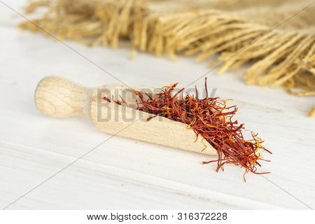 Lot Of Whole Dry Shaffron Thread With Wooden Scoop And Jute Cloth On White Wood