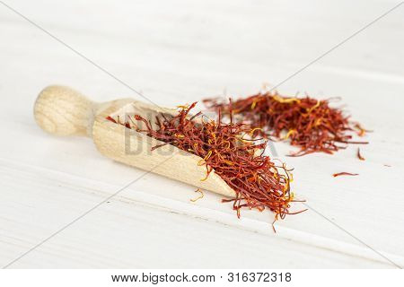 Lot Of Whole Dry Shaffron Thread And Heap Near With Wooden Scoop On White Wood