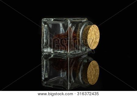 Lot Of Whole Dry Shaffron Thread In Glass Bottle With Cork Cap Isolated On Black Glass