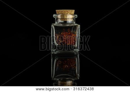 Lot Of Whole Dry Shaffron Thread In Glass Bottle With Cork Cap Isolated On Black Glass