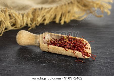 Lot Of Whole Dry Shaffron Thread With Wooden Scoop And Jute Cloth On Grey Stone