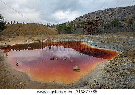 Abandoned Copper Mine With Red Toxic Water And Dramatic Stormy Cloudy Sky At Mitsero Area In Cyprus